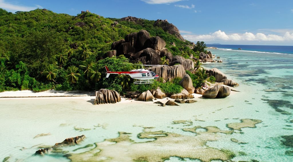 helikopter som flyr over vakker strand med steinformasjoner i granitt